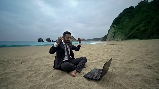 商人在海滩上使用电脑- 4K分辨率视频素材