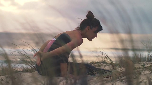 美丽的中年妇女在海滩上练习瑜伽日落在大西洋在法国南部。视频素材