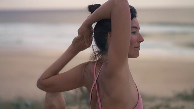 美丽的中年妇女在日落时在法国南部大西洋的海滩上练习瑜伽。视频素材