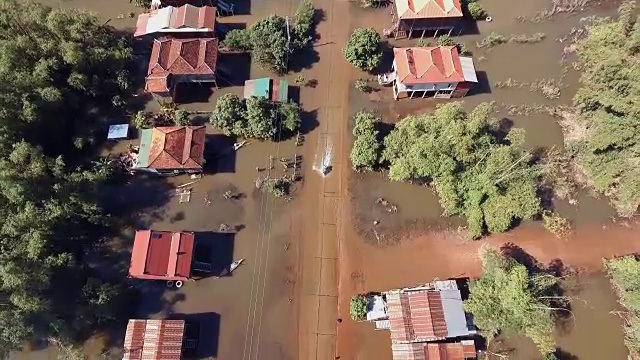 垂直飞过被水淹没的街道上的摩托车，穿过一个乡村视频素材