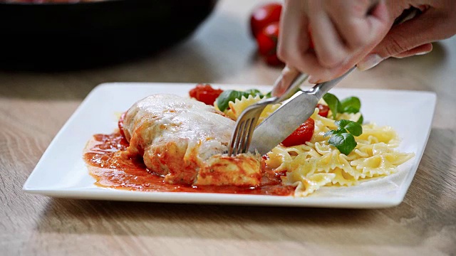 意大利食物:鸡肉配西红柿和意大利面特写。女孩吃视频下载