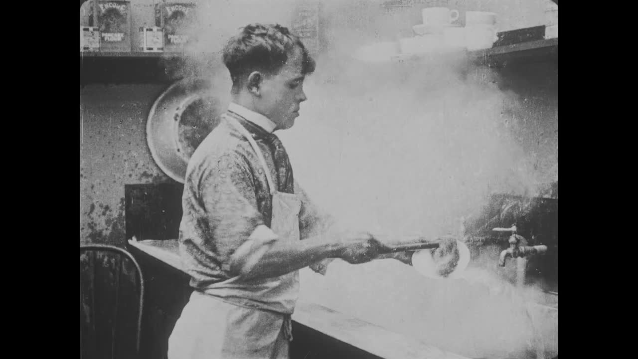 1918年，专注的男孩在沥干板上用狗擦洗热气腾腾的盘子视频下载