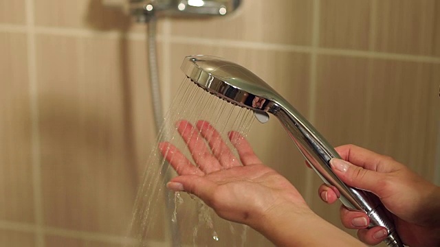 一个女孩的特写镜头打开了淋浴的水。视频素材