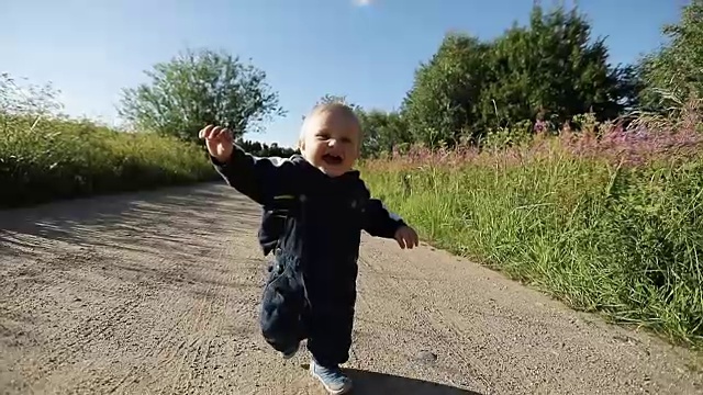 一个一岁的小男孩在沙路上跑着，笑着。视频素材