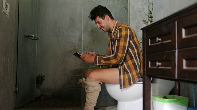 坐着上厕所用手机的年轻人在网上聊天视频素材