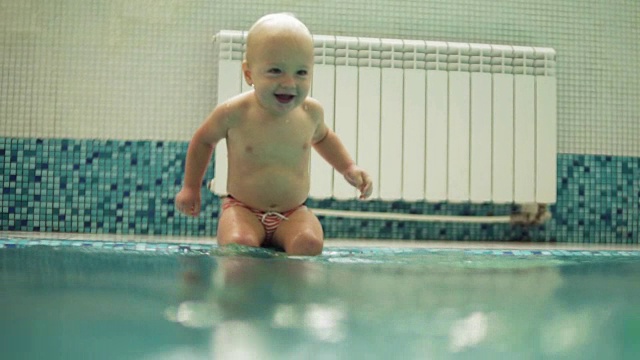 快乐微笑的幼童是跳跃和跳水下的水在游泳池。一个水下拍摄。Slowmotion视频素材