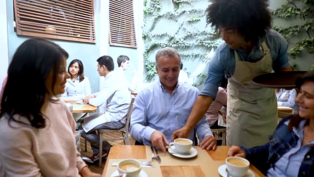 友好的黑人侍者为一群人提供咖啡视频素材