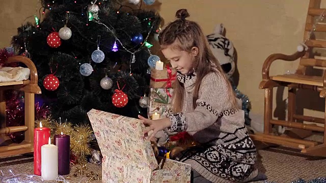 圣诞树旁的美丽小女孩打开了一个礼物盒，里面装着圣诞老人送的新年礼物视频素材