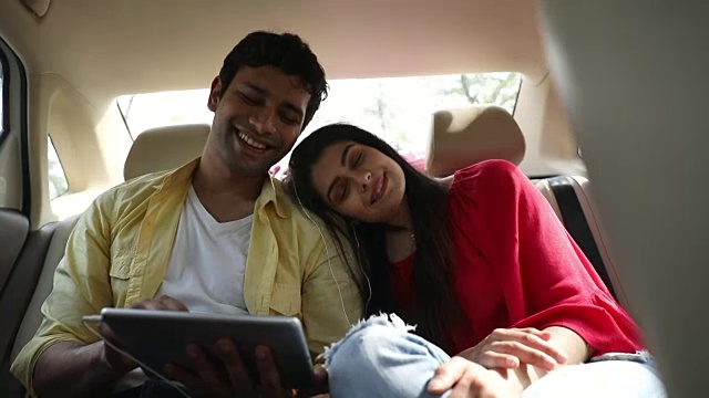 在印度德里，一对夫妇在车里用平板电脑听音乐视频素材