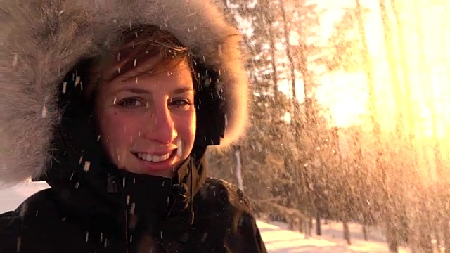 慢镜头:晶莹的雪花落在阳光下，快乐的年轻女子面前视频素材