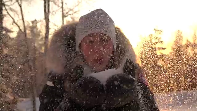 慢镜头:性感的女人在神奇的冬日日出时吹着白色的雪花视频素材