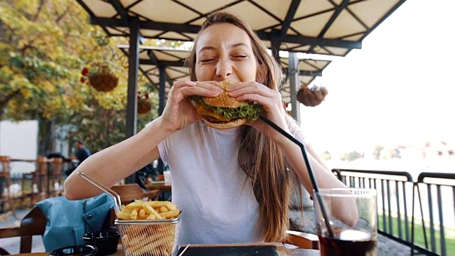 有趣的饿女人在咬她的汉堡视频下载
