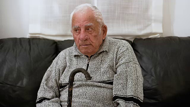 悲伤孤独的老人看了看靠在拐杖上的照相机视频素材