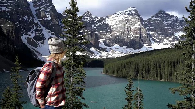 女子站在岩石上望着山景湖景，沉思大自然视频素材