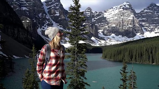 女子站在岩石上望着山景湖景，沉思大自然视频素材