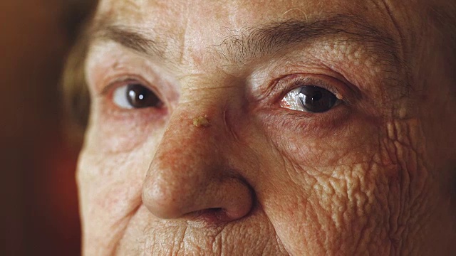 在老妇人的眼睛上的特写肖像:悲伤的老妇人的肖像视频下载