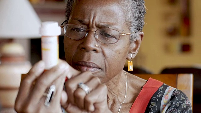 非裔美国老年妇女试图阅读她手中的药瓶标签视频素材