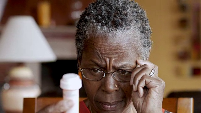 非裔美国老年妇女戴眼镜读她的处方瓶视频素材