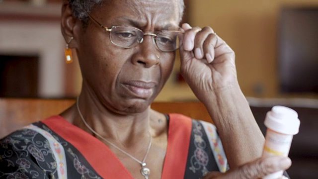 黑人老年妇女戴上眼镜读她的处方瓶视频素材