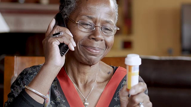 一位黑人老年妇女正在用无绳座机续药视频素材