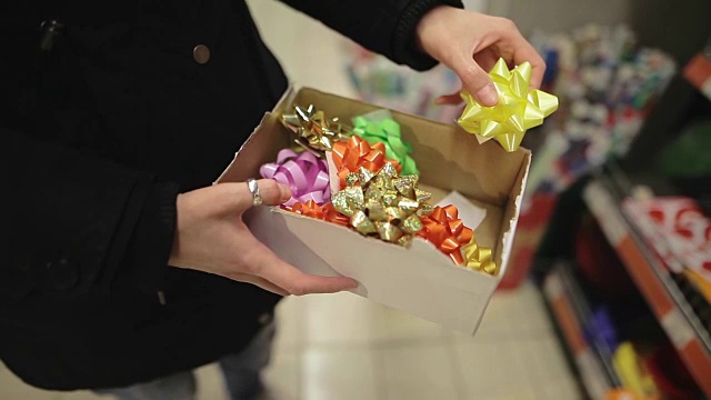 圣诞女人购物装饰圣诞树。一个年轻漂亮的女孩在超市里挑选蝴蝶结作为新年礼物视频下载