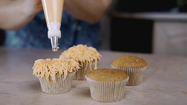 用橘子奶油装饰纸杯蛋糕。用烹饪袋糖果机做松饼视频素材