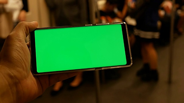 一名男子在火车上拿着绿色屏幕的手机视频素材