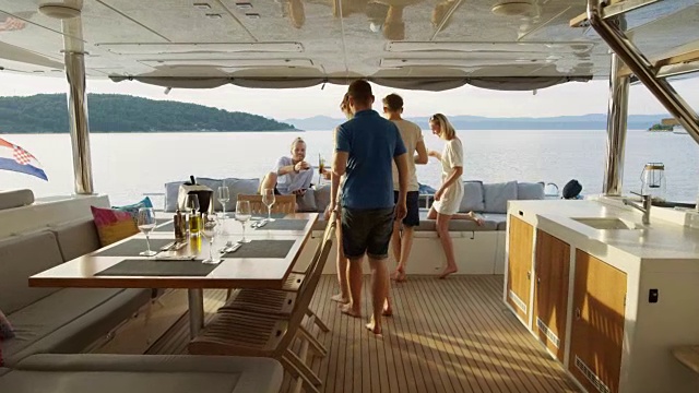 一群成功的年轻人与他人一起在游艇的船尾与鸡尾酒。背景:平静的海洋和岛屿。视频素材