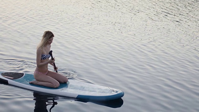 一个年轻女子坐在冲浪板上望着大海。视频素材