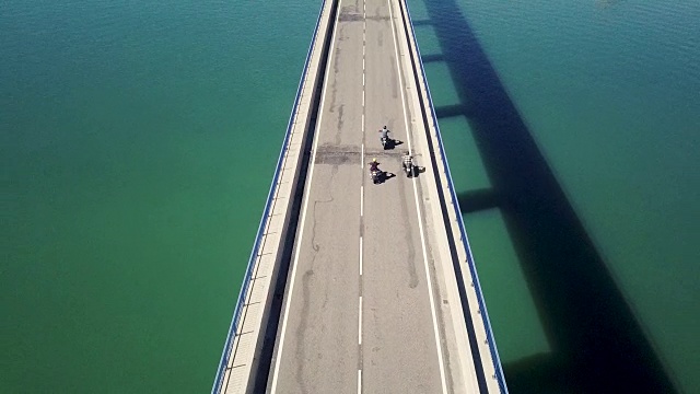 鸟瞰图的摩托车和骑摩托车的人骑过一座公路桥视频素材
