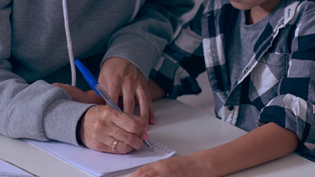 母亲帮助儿子学习在抄写本上写数字视频素材