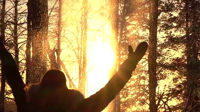 慢镜头:顽皮的女孩在金色的夕阳下向空中抛雪花视频下载
