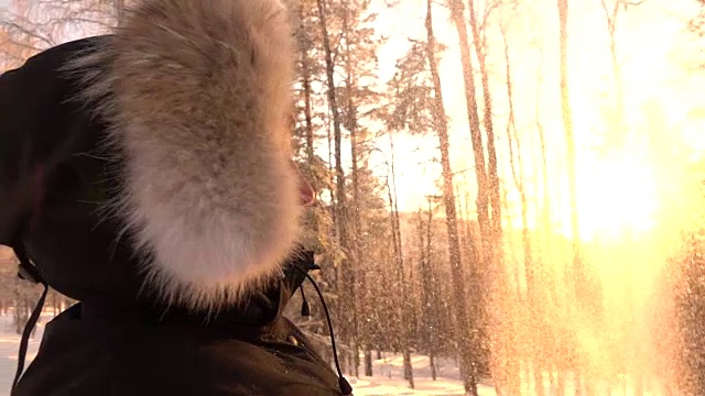 近距离观察:日落时分，一个微笑的女孩在森林里向空中抛出闪闪发光的雪花视频素材