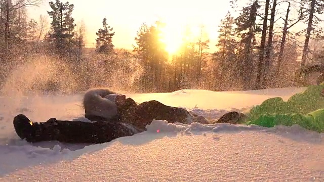 慢镜头:金色的夕阳下，快乐的女孩在山上的雪地里制作雪天使视频素材