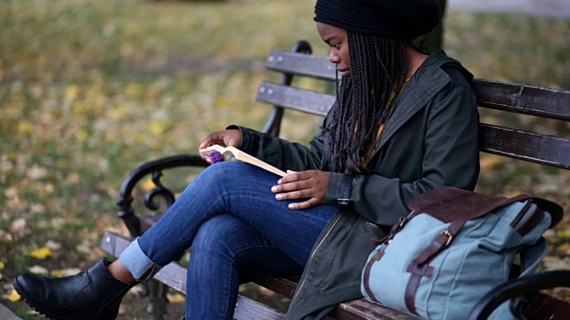 在公园长椅上阅读的富有想象力的女人视频素材