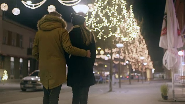 一对年轻夫妇在圣诞彩灯下散步视频素材