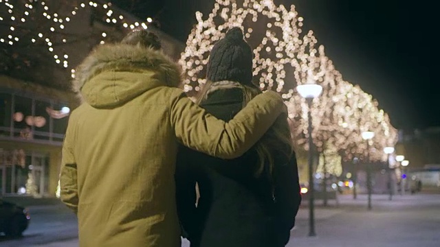 一对快乐的年轻夫妇在圣诞节期间走在城市里视频素材