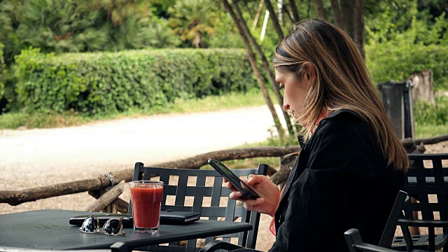 金发商务女人的简介与扬声器在智能手机上交谈-室外视频素材