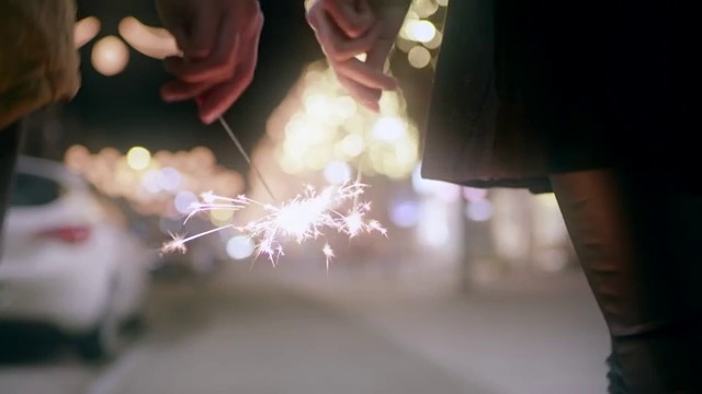 一对情侣手拿烟花走在圣诞节的街道上视频下载