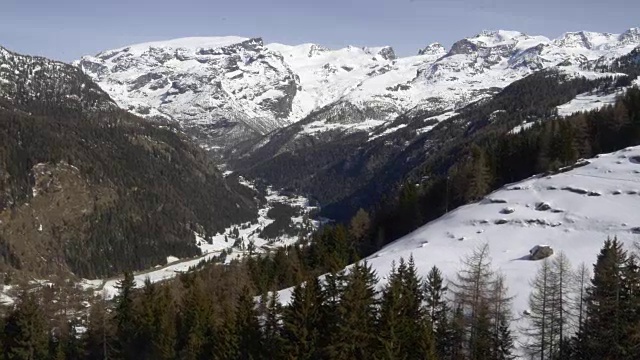 冬季无人机建立雪山下的森林森林山谷。雪山在户外自然。向后飞行。旅行探索阿尔卑斯山，4k俯视图视频视频素材