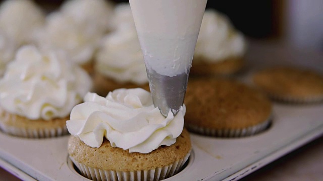用烹饪袋、糖果机制作纸杯蛋糕。把奶油涂在美味的松饼上视频素材