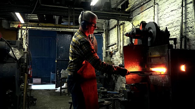 铁匠将金属从熔炉转移到动力锤视频素材