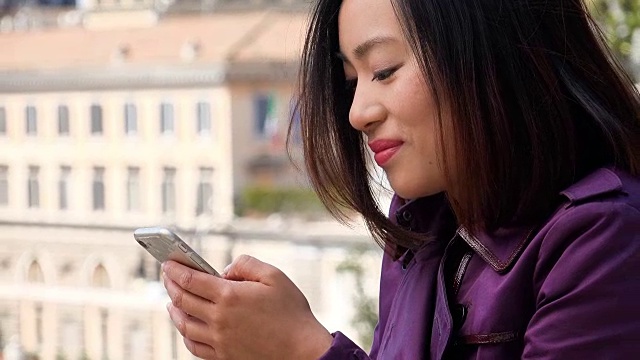年轻的亚洲女性使用智能手机的资料，城市背景视频素材
