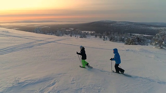一对活跃的夫妇在日出时穿着雪鞋爬上拉普兰雪山的斜坡视频下载