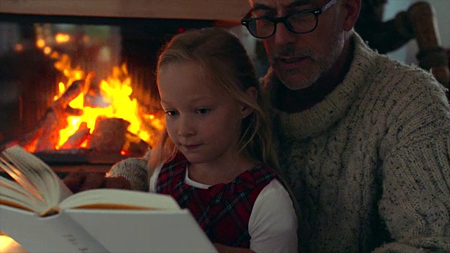小女孩和爷爷在壁炉旁边看书视频素材