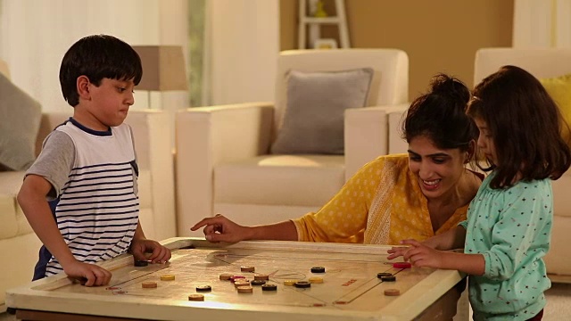 印度德里，一名成年妇女在家里和她的孩子玩carrom视频素材