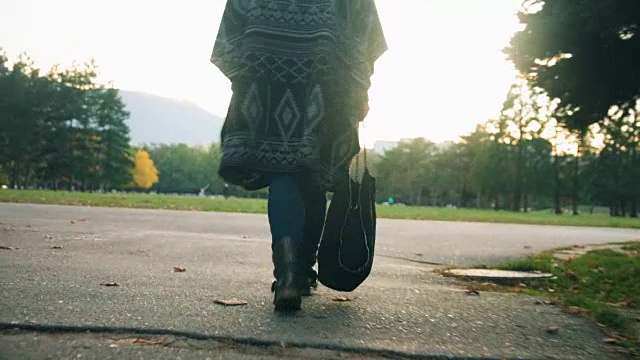 低视角跟踪拍摄的女性的腿行走在城市公园的一条小路上视频下载
