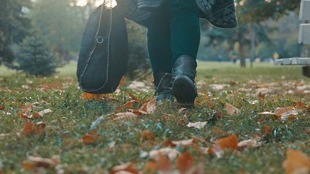 低角度的观点，一个女孩走和通过相机在秋天的落叶视频下载