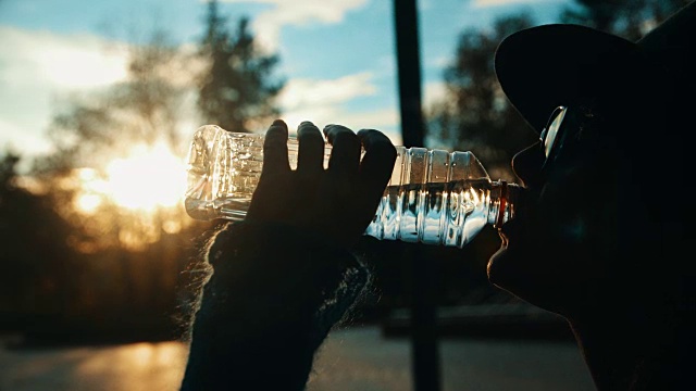 特写慢动作拍摄的女性剪影从一个塑料瓶饮水视频下载