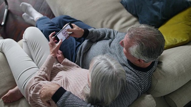 一对老夫妇在用智能手机看女儿的照片视频素材